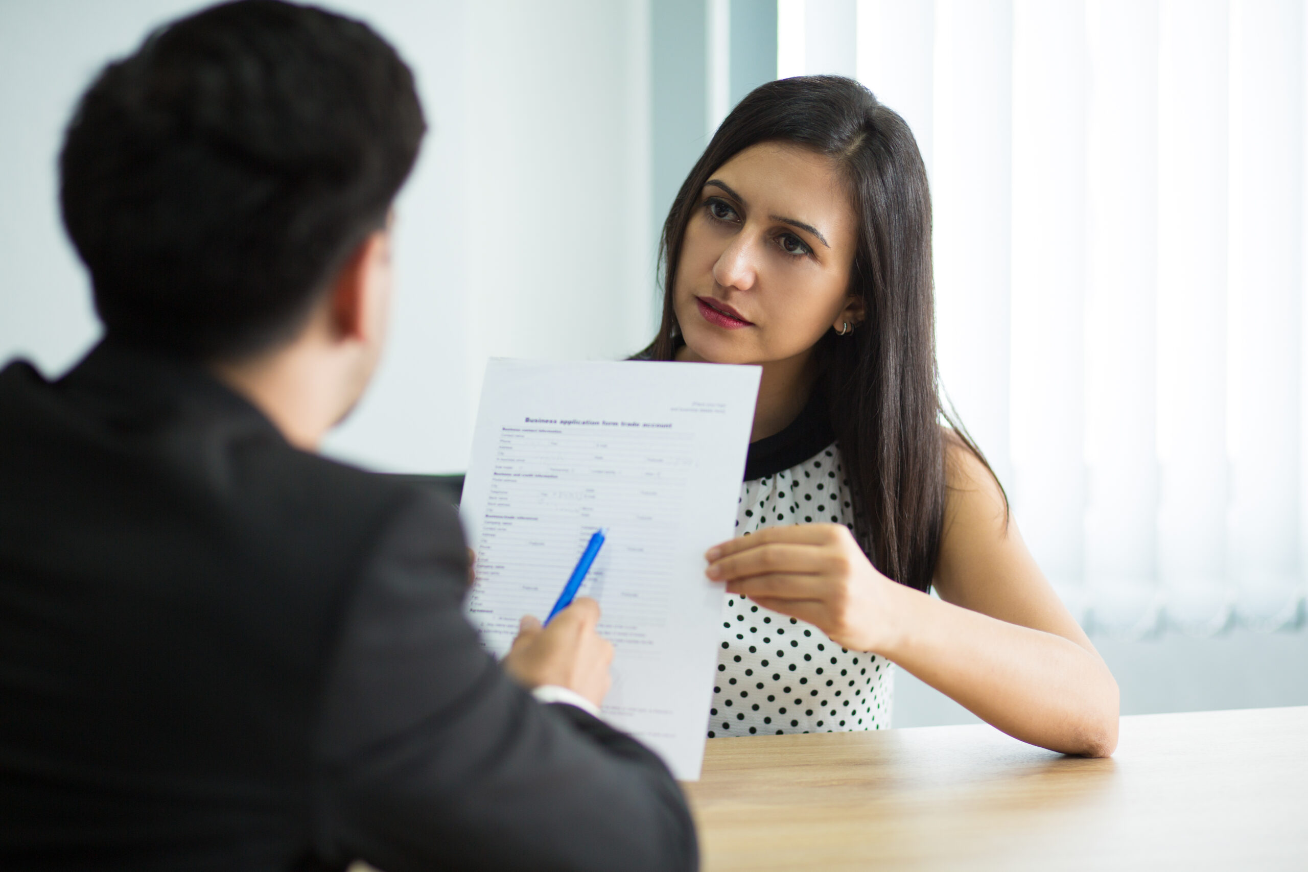 Serious young female manager showing contract to partner. Businessman reading document during meeting. Partnership or interview concept